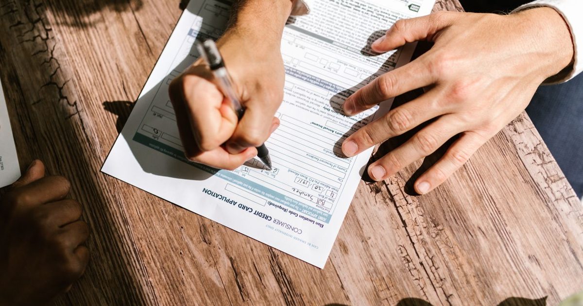 Applicant completing an official form by hand beside supporting documents for an Australian visa application